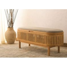 a wooden bench sitting on top of a rug next to a vase