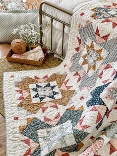 a bed with a quilt on top of it next to a basket filled with flowers