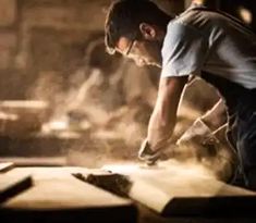 a man working on wood in a workshop