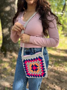 a woman is holding a crocheted bag in her hands and posing for the camera