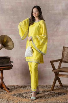 Strut around in this sophisticated Chanderi Kurta and Pants Set in a striking lime yellow hue. Having a straight fit with beautiful bell-sleeves and plush sliver detailing, this chic set is a perfect pick for the days when you are looking to wear something ultra-chic yet simple!Style Kurta and Pants Set Blooming Lime Yellow Boat Neck Bell-sleeves Straight Fit Knee length kurta Ankle length pants Mirrow work Chanderi fabric Specifications Model height - 5'7" Model wearing - S Bell Sleeves Suit, Yellow Green Outfit, Bell Sleeves Kurti, Straight Kurti Designs, Organza Kurti, Bridal Makeup Videos, Kurta And Pants, Yellow Kurti, Yellow Suit