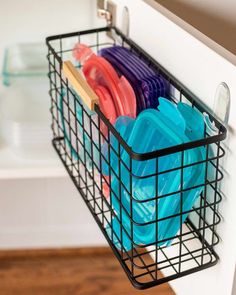 a black wire basket filled with colorful plastic cups and saucers on top of a white counter