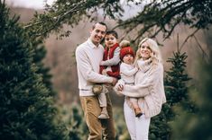 a man, woman and two children are standing in front of some christmas tree trees