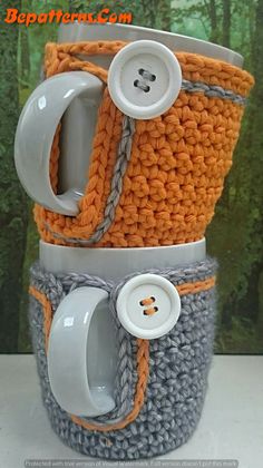 two coffee mugs with buttons on them are stacked in the shape of knitted cups