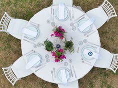 an overhead view of a table set with white linens and pink flowers on it