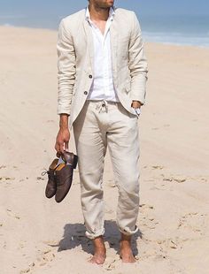 a man is standing on the beach with his shoes in hand and looking off into the distance