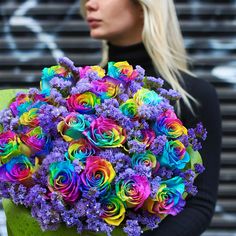 a woman holding a bouquet of colorful flowers