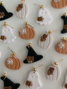 many different colored and shaped pumpkins on a white surface with gold pins in the middle