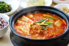 there are many different bowls of food on the table, including rice and tofu