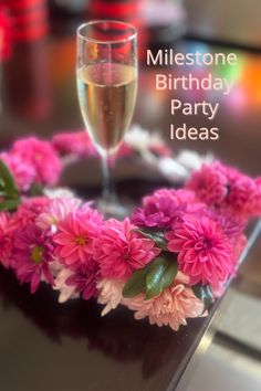 a glass of wine and some pink flowers on a table with the words milestone birthday party ideas