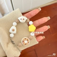 a hand with some fake nails on it and a doughnut in the shape of a teddy bear