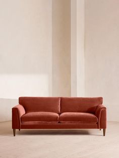 an orange couch sitting on top of a hard wood floor next to a white wall