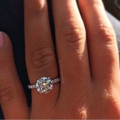 a woman's hand with a diamond ring on top of her finger and the other hand