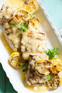 grilled fish with lemon sauce on a white platter