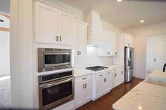 a large kitchen with white cabinets and stainless steel appliances in the middle of the room