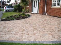 a brick driveway in front of a house with a car parked on the side walk