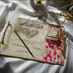 an arabic wedding card with a feather pen and ring on it, surrounded by other items