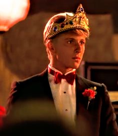 a young man in a tuxedo with a crown on his head and a red bow tie