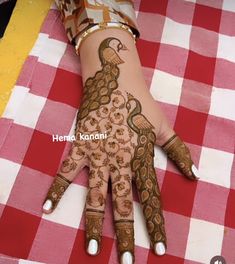 a woman's hand painted with hendi on top of a red and white checkered table cloth