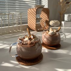 two mugs filled with hot chocolate and marshmallows on top of a table