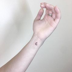 a person's arm with a small crescent tattoo on the middle of their wrist