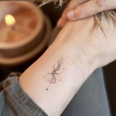 a woman's wrist with a small tattoo on the left side of her arm