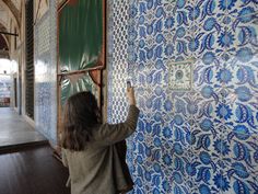 a woman is painting a wall with blue and white designs on it in an old building