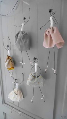 several small dolls hanging from hooks on a wall