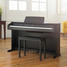 a black piano sitting on top of a hard wood floor next to a yellow chair