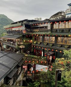 an old building with many balconies and lanterns on the windows is surrounded by greenery