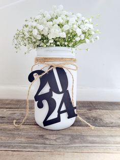 a mason jar filled with white flowers on top of a wooden table