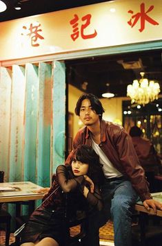 a man and woman sitting in front of a restaurant