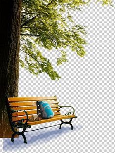 a park bench under a tree in the snow, with a blue pillow on it