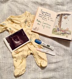 an open book and baby clothes on a bed