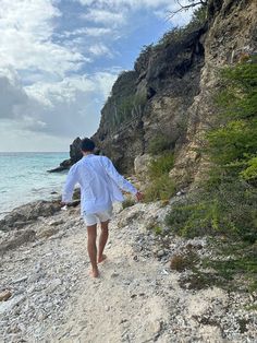 a man walking down a rocky beach next to the ocean