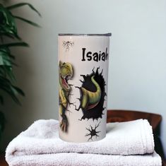 a white coffee cup sitting on top of a stack of towels next to a potted plant