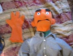 an orange puppet is standing in front of a quilt