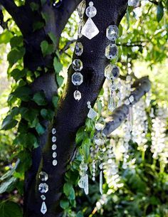 a tree with lots of glass beads hanging from it's branches in the forest