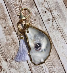 an oyster shell keychain with a tassel hanging from it's side