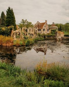 an old house sitting on top of a lush green field next to a pond with water lilies