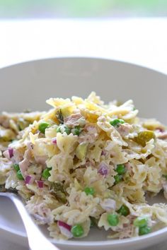 a close up view of a pasta salad with peas and other toppings on a white plate