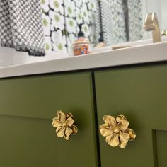 a green cabinet with two gold flowers on it