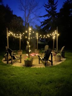 an outdoor fire pit with chairs and string lights on it at night in the yard