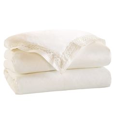 three white sheets stacked on top of each other in front of a white background with an embroidered edge