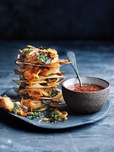 a stack of food sitting on top of a plate next to a bowl of soup