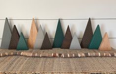 a group of small wooden trees sitting on top of a woven table cloth next to a white wall