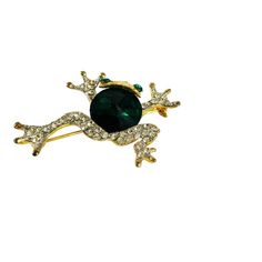 This elegant frog brooch pin, with vintage gold tones and sparkling green eyes, features intricately detailed circular green stones and diamond rhinestone legs. Measuring 1.5 inches in height and 1.75 inches in width, with a depth of 0.25 inches, this brooch is a perfect gift for vintage accessory collectors or frog enthusiasts. It is suitable for special occasions like Mother's Day, Christmas, and birthdays. Despite one tiny missing stone, the pin is in excellent condition. Green Round Brooch For Formal Occasions, Eyes Features, Frog Brooch, Green Stones, Green Stone, Vintage Accessories, Green Eyes, Vintage Gold, Brooch Pin