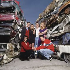 a group of people posing in front of a pile of junk