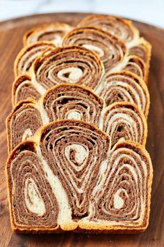 slices of cinnamon roll sitting on top of a wooden cutting board