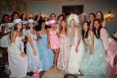 a group of women in dresses and hats posing for a photo with one woman wearing a veil